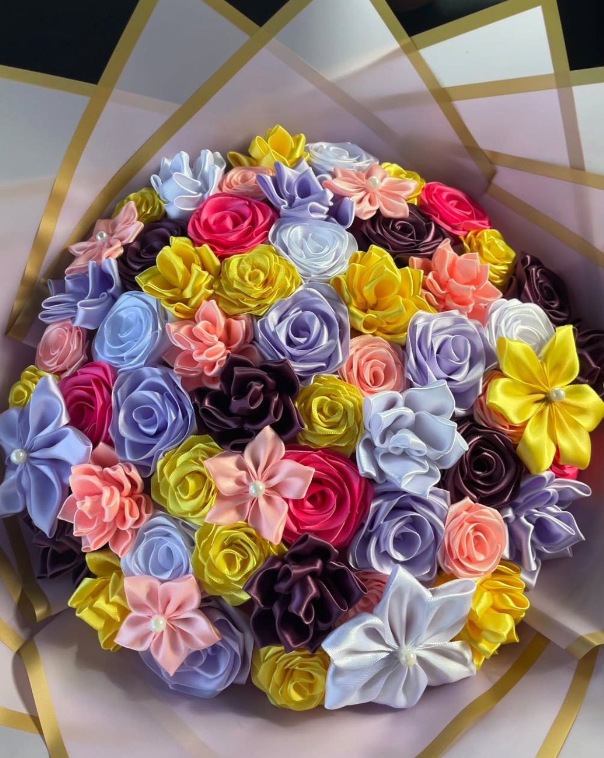 Hands arranging handmade ribbon roses